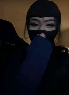 a woman wearing a face mask and covering her mouth with a black cloth in the dark