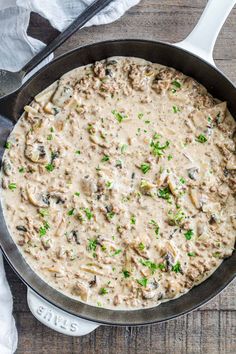 a skillet filled with mushroom gravy on top of a wooden table