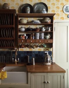 an old fashioned kitchen with wooden cabinets and dishes on the shelf above the sink,