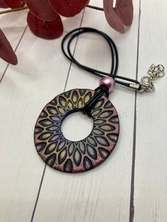 a necklace with a circular pendant hanging from it's side on a wooden table