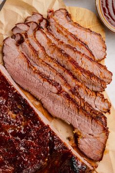 sliced meat sitting on top of a cutting board next to sauces and ketchup