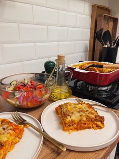 two plates with lasagna casserole and salad on the counter next to an oven