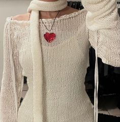 a woman wearing a white sweater with a red heart on the front and neckline