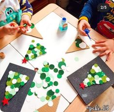 two children are making christmas trees out of construction paper and glue on top of the table