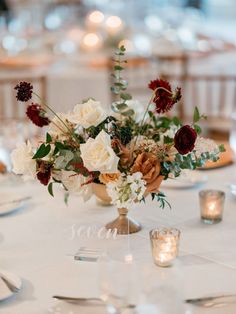 a centerpiece with flowers and candles on a table