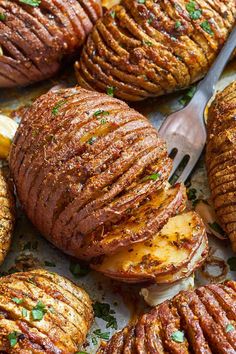 baked potatoes on a sheet pan with a knife and fork next to them, ready to be eaten