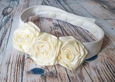 a white headband with three flowers on top of it, sitting on a wooden surface