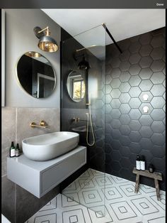 a modern bathroom with hexagonal tiles on the floor and walls, along with a round mirror