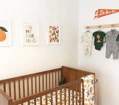 a baby crib in a white room with orange and green wall art on the walls