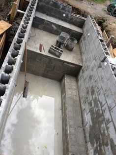 an unfinished building with concrete walls and pipes in the ground, surrounded by other construction materials