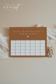 a brown and white calendar sitting on top of a table next to a pile of blankets