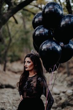 a woman in a black dress is holding some balloons and posing for the camera with her hands on her hips