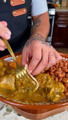 a person is spooning some food out of a bowl with beans on the side