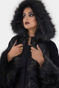 DARK AURA.- Soft velvet with faux fur trims.- Statement cloak.- Uneven hem.- Front tie with moon hardware.- Oversized hood.- Fully lined.- Relaxed fit.With KILLSTAR branding, Shell fabric : 95% Polyester 5% Elastane, Lining: 100% Polyester, Trim : 59% Acrylic 41% Polyester.Do no wash / Do not bleach / Do not tumble dry / Do not iron / Do not dry clean. Imported. Black Fluffy Hooded Outerwear, Black Hooded Fur Coat With Faux Fur Lining, Winter Outerwear With Detachable Hood For Alternative Fashion, Black Hooded Fur Coat With Detachable Hood, Witchy Hooded Outerwear For Cosplay, Winter Costume Outerwear With Faux Fur Lining, Witchy Long Sleeve Winter Outerwear, Witchy Hooded Winter Outerwear, Witchy Winter Outerwear For Larp