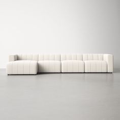 a large white couch sitting on top of a cement floor next to a gray wall