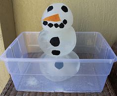 a plastic container with a snowman made out of toilet paper sitting on top of it