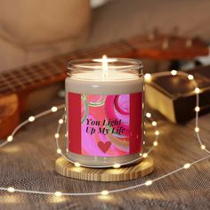 a lit candle sitting on top of a wooden table next to a string of lights