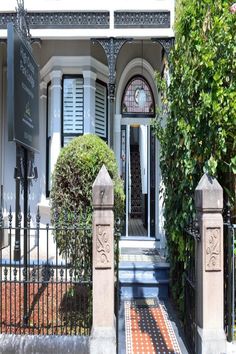 the entrance to an old style house with wrought iron fence