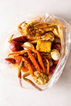 crab legs, carrots, corn and potatoes in a plastic bag