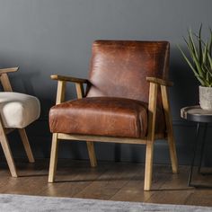 a brown leather chair sitting next to a table with a potted plant on it