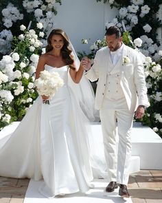 a bride and groom walking down the aisle at their wedding ceremony with white flowers in the background