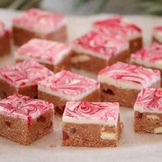 there are many pieces of cake with pink icing on it and white frosting