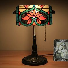 a lamp that is sitting on top of a wooden table next to a photo frame