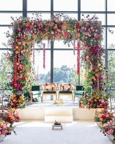 an aisle decorated with flowers and greenery for a wedding ceremony in front of a large window