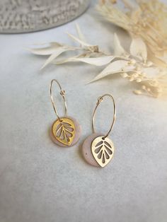 the gold leaf earrings are on display next to some dried flowers and leaves in front of them