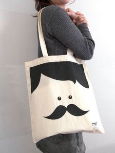 a woman holding a tote bag with a mustache on it