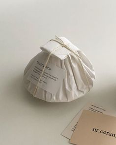 a white paper bag tied up with twine on top of a table next to an envelope