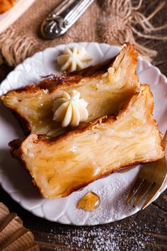 two slices of pineapple on a white plate with fork and knife next to it