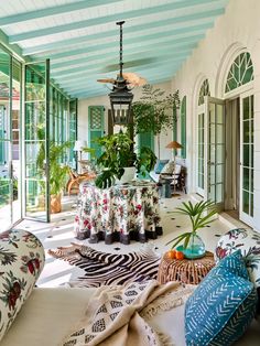 a living room filled with lots of furniture and plants on top of the couches