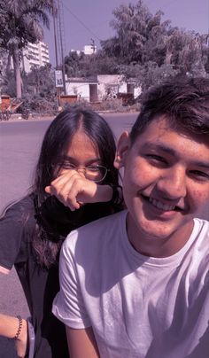 two young people posing for a photo on the street with palm trees in the background