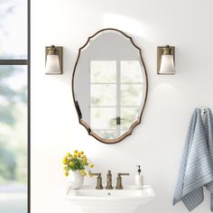 a white sink sitting under a mirror next to a wall mounted faucet in a bathroom