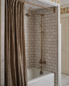 a bathtub and shower in a bathroom with white tile walls, flooring and curtains