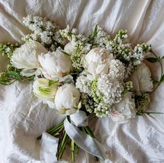 a bouquet of white flowers laying on top of a bed