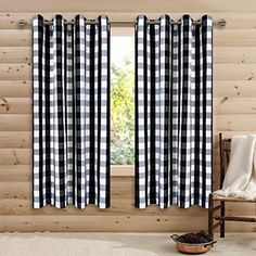 a black and white checkered curtain hanging in front of a window with a chair next to it