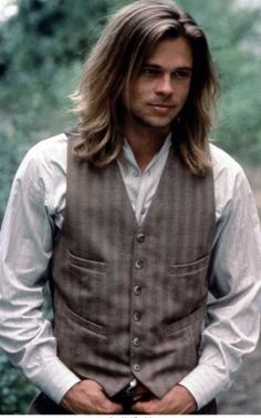 a man with long hair wearing a vest