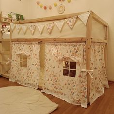 a child's play house with curtains on the top and bottom half, in a room with hardwood floors