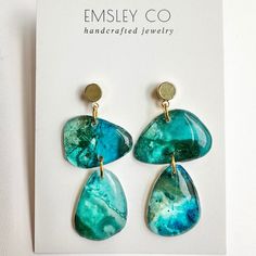 the earrings are made from green and blue marbles with gold earwires on them