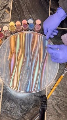 a person in purple gloves is painting on a metal plate