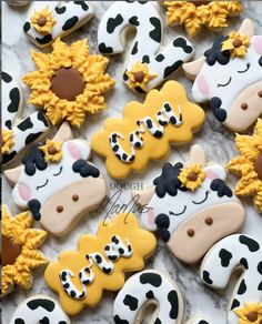 decorated cookies are arranged in the shape of cows and sunflowers