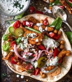 a pita filled with chicken, vegetables and tzatzh on top of a table