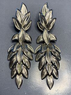 LOVELY TRIFARI VINTAGE 1980's Silver leaf Design Long Dangly Drop Clip On Earrings Signed Statement Elegant Glamour Runway Designer Couture. Wonderful earrings with a push back clip in a fantastic leaf design, signed on the clip at the back with the crown above Trifari. Measurements: 6.6cm by 2.2cm Condition: In ABOVE excellent vintage condition, The clips are secure and tight. Please look at the photos as they are truly representative of the condition of this amazing earrings. All our items are priced including delivery tracked and signed for and tracking number will be provided after postage.   Don't hesitate to ask any questions or need further information. Use the discount code WAYOFLIFE20 to receive €20 discount when purchasing two items from our shop. PLEASE FEEL FREE TO CHECK OUT OU Silver Leaf-shaped Earrings For Party, Leaf-shaped Metal Earrings For Party, Leaf-shaped Metal Jewelry For Party, Silver Leaf-shaped Jewelry For Party, Leaf-shaped Metal Party Jewelry, Amazing Earrings, Silver Leaf, Leaf Design, Clip On