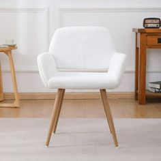 a white chair sitting on top of a hard wood floor next to a wooden table