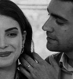 black and white photograph of a man fixing a woman's ear