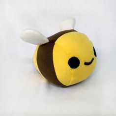 a yellow and brown stuffed animal with a bee on it's head, sitting in front of a white background