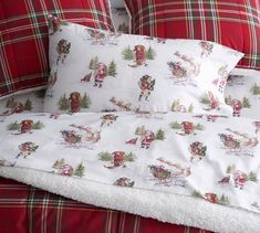 a bed with santa claus on it and plaid comforter in the middle, along with two pillows