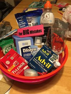 a pink bowl filled with lots of different types of toiletries on top of a wooden table